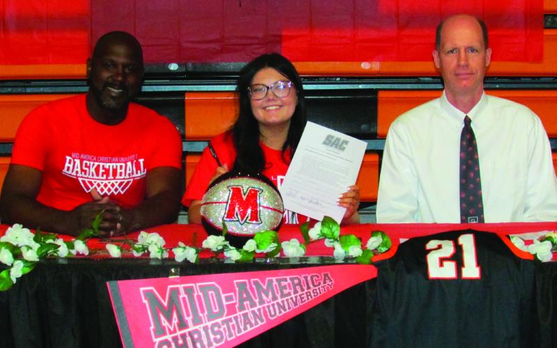 Jaylee Thomas proudly holds up her recently signed MACU intention letter between Coach Ivan McFarlin and Coach Chad Dickerson, who she said was reason she pursued basketball during high school.