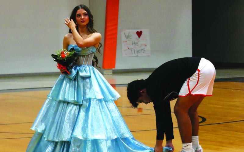 Koda Chavez attends to the finer points of his homecoming escort duties as he arranges Mya Bridgeman’s dress.