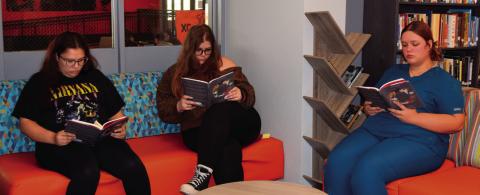 Addison Elliott, Zaylee Odom, and Lauralei Casteel sit in the High School Library reading “How to be a Good Creature” by Sy Montgomery.