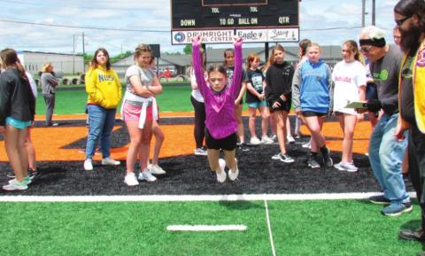Danny Malone takes to the air in the 5th grade girls’ long jump event, as Lions Club members cheer her on during the Junior Olympics on May 3.