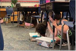Fourth-grade students at Plaza Towers Elementary School in Moore practice Drop, Cover and Hold On under their desks during an earthquake safety presentation by the Oklahoma Geological Survey on Wednesday, Oct. 9, 2024. Courtesy of ODEM