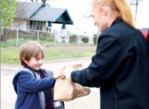 Liger Phelps receives his breakfast and lunch sacks from Keystone Food Services employee Kristy Barnes at Cushing Upper Elementary Monday. Close to 400 meals were provided at two separate sites in Cushing.