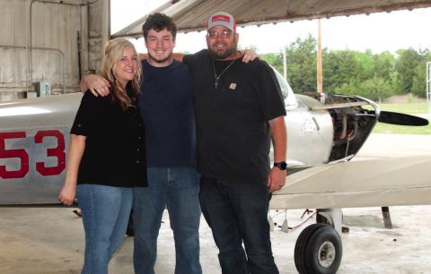 Jacob O’Kelley stands between his parents — Jazmine and Jack — in front of a small single engine aircraft.Photo by DeAnna Maddox.