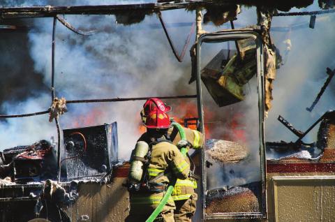 Members of the Cushing Fire Department work to extinguish a burning RV on East Vine, last week. Photo by Allie Prater