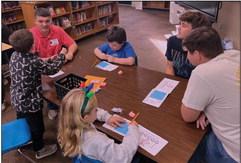 Cushing High School students Cason Brandon, Tommy Rolfe, and Tyler Norman work with second graders to figure out the best house to withstand the Big Bad Wolf’s huffs and puffs.