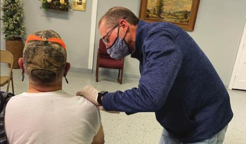 John Lemley, pharmacist at Baker Pharmacy, administers the COVID-19 vaccine to patient Hubert Bowley.