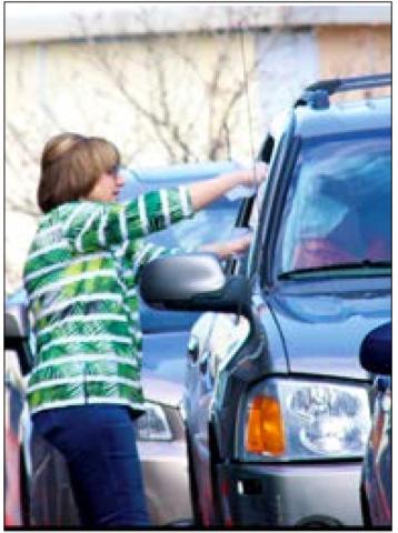 Cushing Senior Center Director Debbie Brown hands a meal to a waiting senior in the parking lot of the senior center.