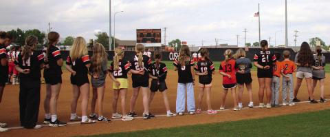 Cushing Tiger youth athletes join the varsity Lady Tigers on the field for the Star Spangled Banner during the youth night game against Chandler last week. Photo by Allie Prater.