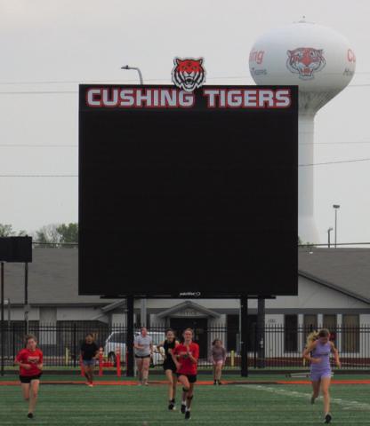 Students race across the football field in front of the recently installed Jumbotron at O’Dell Field. The digital video board will be enhancing Friday nights and other field events with live video, score board display, and eventually instant replays.