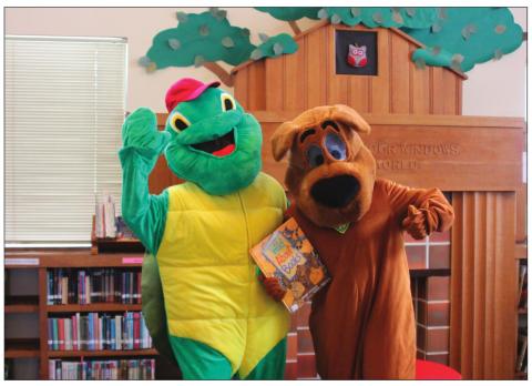 Beloved children’s book characters, Scooby-Doo and Franklin the Turtle, hold one of the many books available at the Cushing Public Library.