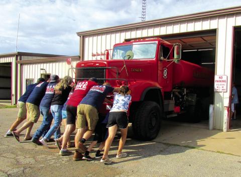 Cpt. Patrick Johnston, Lt. Jansen Callanan, Chief Mike Callanan, Asst. Chief Tory Sweet, Captain Casey Walters, and firefighters Ron Pendergraff, Kyle Wolff, Hailey Johnston, Samantha Dixon, and Jarrod Molloy as well as community members came together to push Tanker 1 into the firehouse during the traditional push-in ceremony held on Sept. 24. Photo by DeAnna Maddox