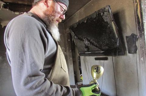 Jeremy Fincher holds a “worlds best dad” trophy while standing in the ruins of his family’s home.