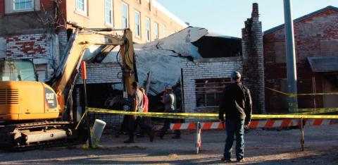 A crew from TKO Construction works to take down a collapsed building at 110 West Broadway in Cushing Monday.