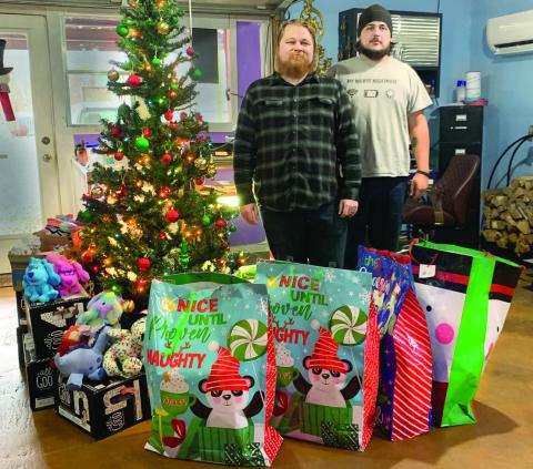 Arcane Panther Tattoo Studio owner and tattoo artist Jeremiah Smith, and apprentice Bradley Couch stand next to the gifts that have been donated so far for the third annual Toys for Tats Toys Drive. Photo by Allie Prater