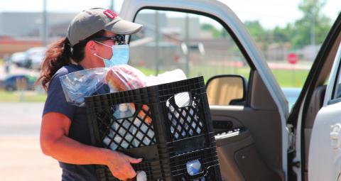 Shelly Wilson works hard carrying crates filled with groceries out to one of the participants during the Our Daily Bread event on Aug. 25 at the Cushing Community Food Pantry.