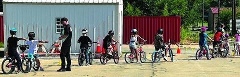 Participants of the Brandon Hise Memorial Bike Rodeo make their way through an obstacle course as Cushing Police Department members monitor and instruct in safe practices.