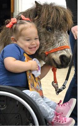 Agra first grader Allie Castor smiles big as she hugs Pete, one of the many horses cared for by The Right Path. Photo by Selah Ocker