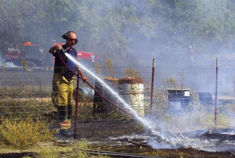Cushing Fire Department Lieutenant James Blevins uses a tanker hose to cool off one of the last hotspots following the cooperative efforts of several local departments to put out a grass fire close to Agra last Friday, Sept. 30. Photo by DeAnna Maddox