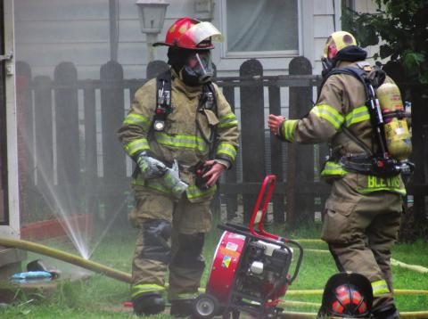 Firefighters Dakota Shadowen and James Blevins takes a moment to catch their breath before continuing to work against the fire at 1002 West Broadway on Tuesday, May 24. Photo by DeAnna Maddox
