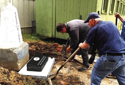 Cimarron Valley Historical Society President Farrel Kleckner, foreground, and Zach Howser, owner of Williams Monuments square up the commemorative stone in front of the recently placed intersection marker at Centennial Park.