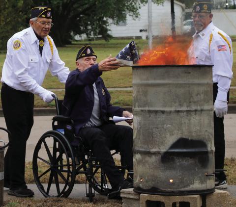 Legionnaire Tom Jones retires a flag while Legionnaire Don Tyson and Legionnaire Tim Potter watch on.