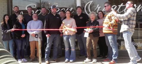 Members of the Cushing Chamber of Commerce stand with the owners of Spoken Creation, Kyle and Rachel Williams, during the ribbon cutting ceremony in front of their new business on Cleveland. Photo by Cayla DeHaas.