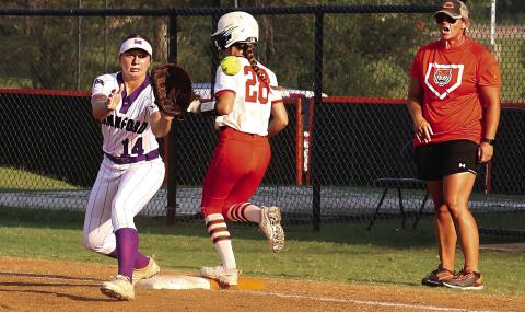 Cushing Lady Tiger junior Romy Withiam makes it to first base seconds before Mannford Lady Pirate first baseman Sydney Webster catches the ball as Lady Tiger head coach Nikki York watches from the coach’s box during the Lady Tigers game Tuesday, Aug 22. Photo by Allie Prater