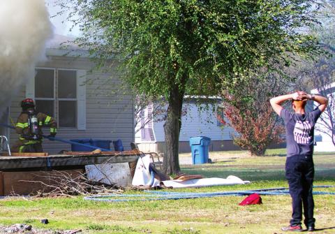 The grandson of the owner of this home on Greenlee watches distraught, as members of the Cushing Fire Department work to extinguish the fi re inside the building.