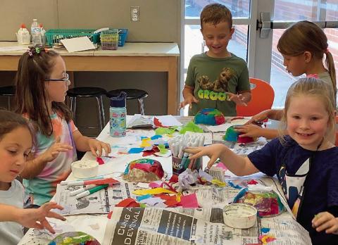 Younger art students embellishing paper mache masks during the 31st Summer Art Camp that was recently completed.