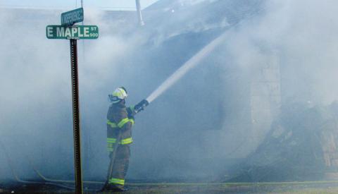 Deputy Fire Chief Dalton Novotny keeps a steady stream of water running over the home on the corner of Maple and Independence as the fire comes under control. The Cushing Fire Department stayed on scene for two hours to watch for hot spots and possible flares.