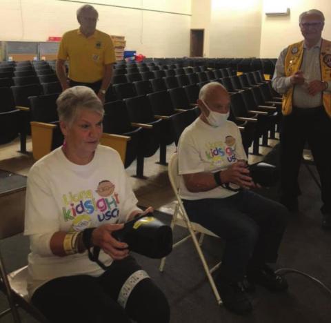 Cushing Lions Club members Lou Griffi n and Jim Pickard hold steady as they handle the cameras for Oak Grove School students being screened, while Tom Cummings and Russell Thurman supervise and hand out stickers in the background.