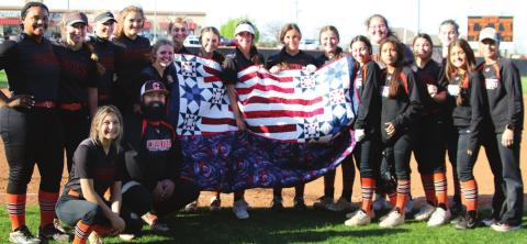 The entire Lady Tiger slowpitch softball team surrounds Assistant Coach Josh Encinas (kneeling) after he received his Quilt of Valor between games last Tuesday.