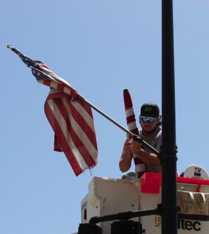 Apprentice lineman with the Electric Distribution department, Tagun Fittje, was replacing damaged flags in the Broadway District last week prior to the holiday festivities. As part of flag etiquette whenever a flag is worn or damaged beyond repair the flag should be destroyed by burning it.
