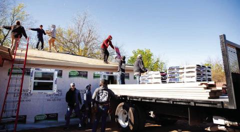 Construction students at Central Tech load shingles on the roof of the house they are building.