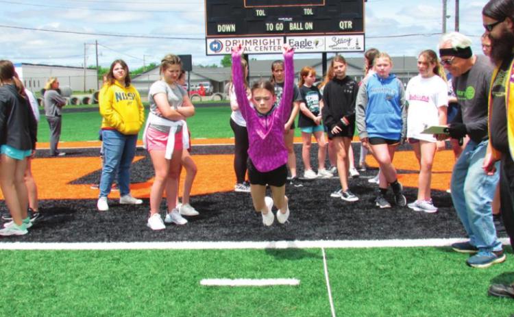 Danny Malone takes to the air in the 5th grade girls’ long jump event, as Lions Club members cheer her on during the Junior Olympics on May 3.