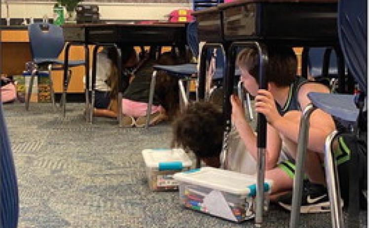 Fourth-grade students at Plaza Towers Elementary School in Moore practice Drop, Cover and Hold On under their desks during an earthquake safety presentation by the Oklahoma Geological Survey on Wednesday, Oct. 9, 2024. Courtesy of ODEM