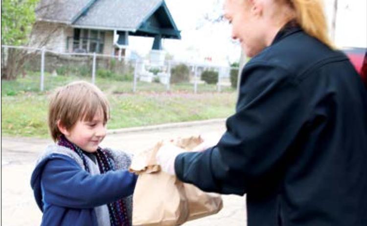 Liger Phelps receives his breakfast and lunch sacks from Keystone Food Services employee Kristy Barnes at Cushing Upper Elementary Monday. Close to 400 meals were provided at two separate sites in Cushing.