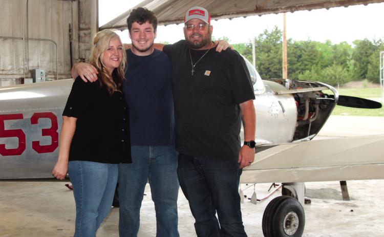 Jacob O’Kelley stands between his parents — Jazmine and Jack — in front of a small single engine aircraft.Photo by DeAnna Maddox.