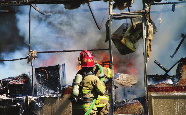 Members of the Cushing Fire Department work to extinguish a burning RV on East Vine, last week. Photo by Allie Prater