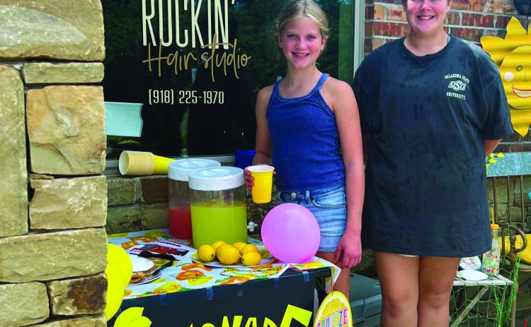 Young entrepreneurs Bentley Meyers and Avery Dooley cheerfully sell lemonade in the rain from their bright and sunny lemonade stand in front of the Rockin’ Hair Studio on Main Street, in Cushing, last week. The girls took advantage of their fi nal full week of summer to raise a bit of cash going into the school year, which starts Thursday in Cushing.