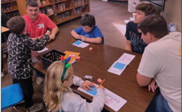 Cushing High School students Cason Brandon, Tommy Rolfe, and Tyler Norman work with second graders to figure out the best house to withstand the Big Bad Wolf’s huffs and puffs.