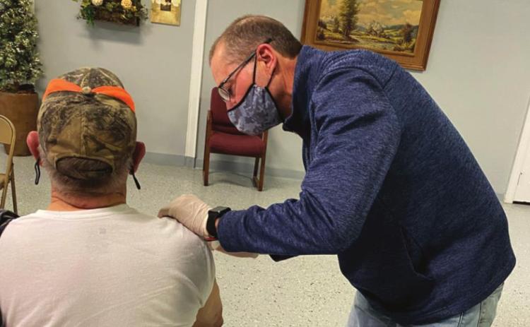 John Lemley, pharmacist at Baker Pharmacy, administers the COVID-19 vaccine to patient Hubert Bowley.