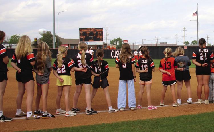 Cushing Tiger youth athletes join the varsity Lady Tigers on the field for the Star Spangled Banner during the youth night game against Chandler last week. Photo by Allie Prater.