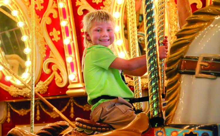 Hutson Boos, of Cushing, celebrates his fifth birthday by smiling upon his kingdom (The Payne County Free Fair) atop his noble steed (while riding the carousel) Thursday, Aug. 29. Photo by Allie Prater