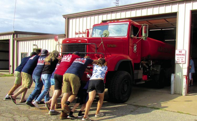 Cpt. Patrick Johnston, Lt. Jansen Callanan, Chief Mike Callanan, Asst. Chief Tory Sweet, Captain Casey Walters, and firefighters Ron Pendergraff, Kyle Wolff, Hailey Johnston, Samantha Dixon, and Jarrod Molloy as well as community members came together to push Tanker 1 into the firehouse during the traditional push-in ceremony held on Sept. 24. Photo by DeAnna Maddox