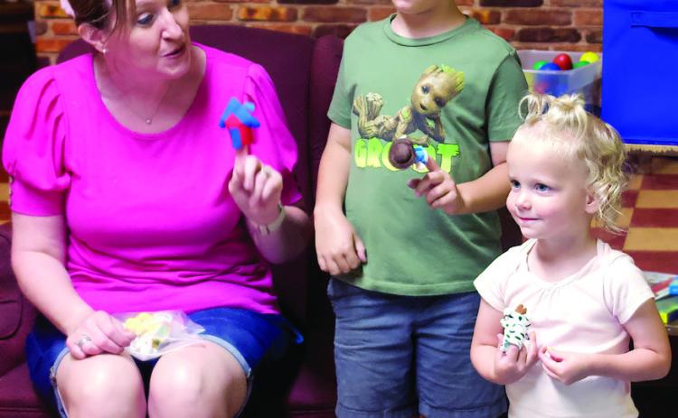 Toddler Music Time instructor Regina Brown shows siblings Parker and Blake Stacy how to use finger puppets during the first Toddler Music Time of the summer held at the Cushing Public Library Monday, June 17. Photo by Raynee Howell.