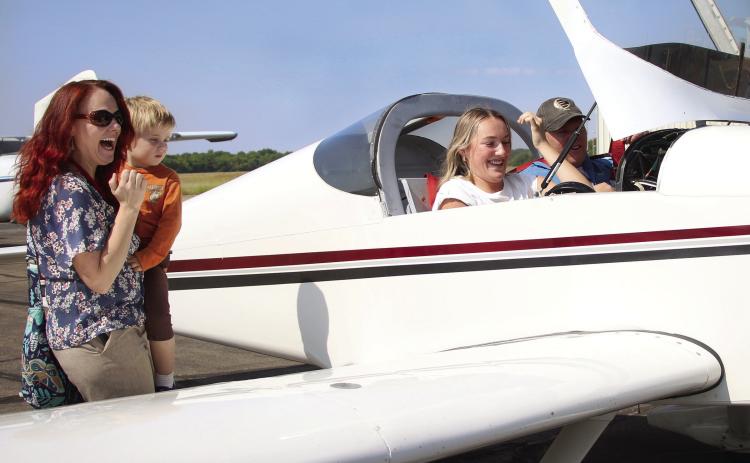CHS aviation teacher Dr. Jessica Sigle and her son Timothy share their excitement with aviation student Emery Turner as she sits in the cockpit of Matt Steward’s RV kit plane after logging her first flight hour.