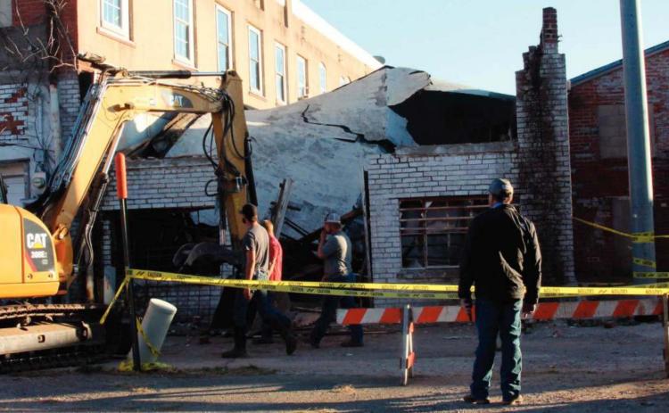 A crew from TKO Construction works to take down a collapsed building at 110 West Broadway in Cushing Monday.