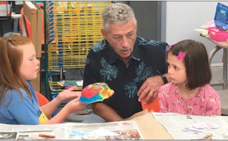 Representative John Talley discusses how to make a mask with Hadley Marshall (left) and Piper Sigle during the last week of the most recent Cushing Art Camp held at Cushing Middle School.