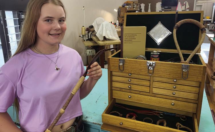 Mercedes Cargill with her rawhide braiding box, filled with tools and items she’s braided, such as a bosal (top right), bracelets (bottom) and quirt (in hand).